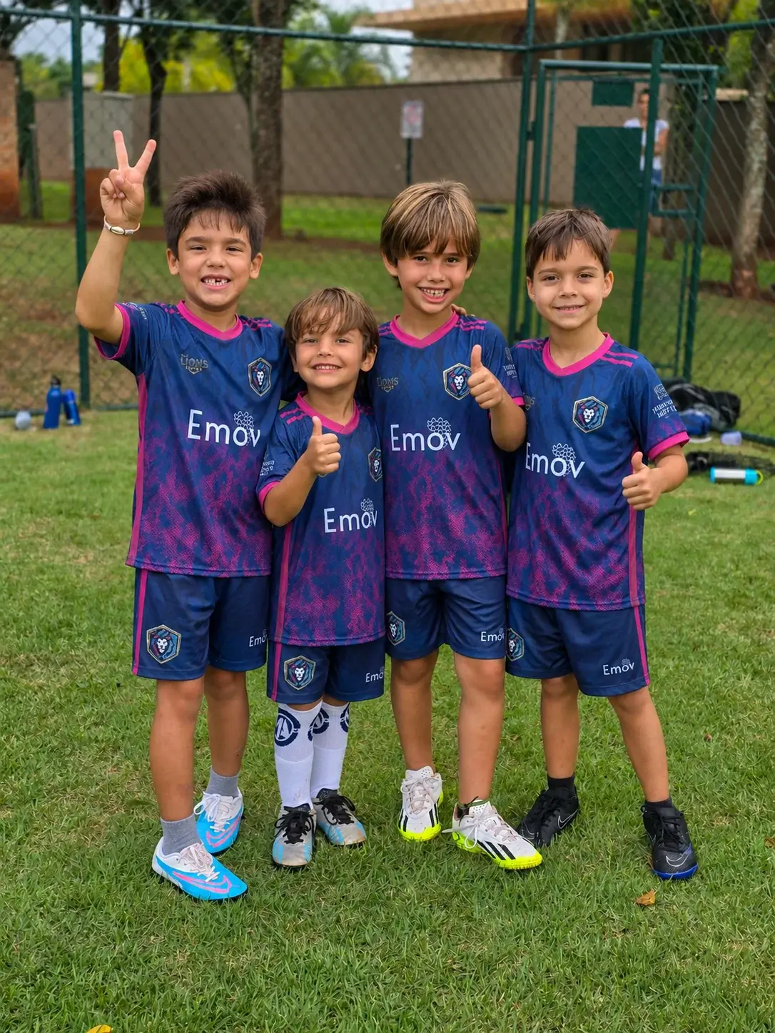 Quatro crianças da M.A Lions Soccer juntas no campo de futebol